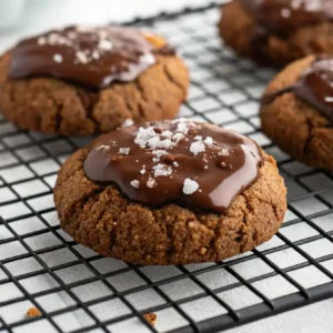 Close-up of a healthy high protein collagen cookie topped with melted sugar-free chocolate and sea salt flakes on a wire rack